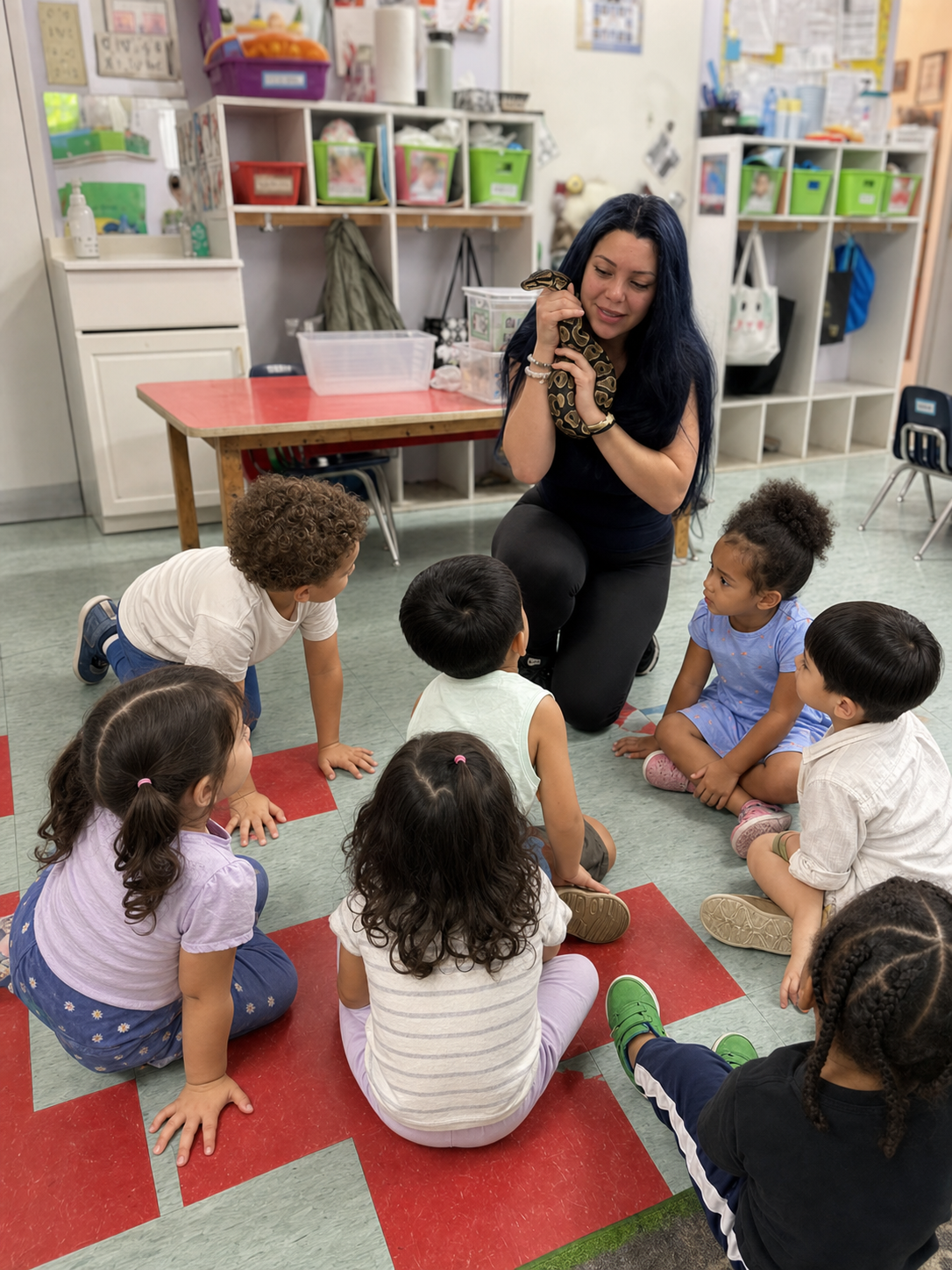 A Little Explorers reptile educator introducing a ball python to a small classroom group